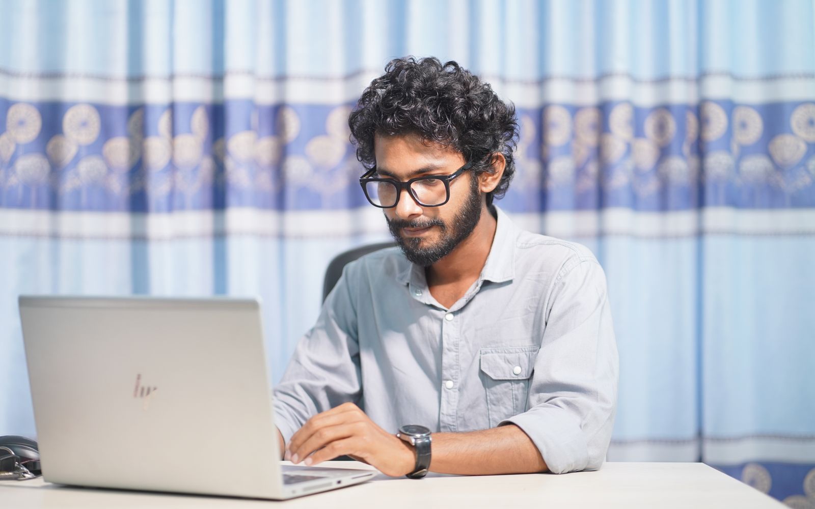 A focused young man using a laptop in a well-lit room. Ideal for themes of productivity and tech.