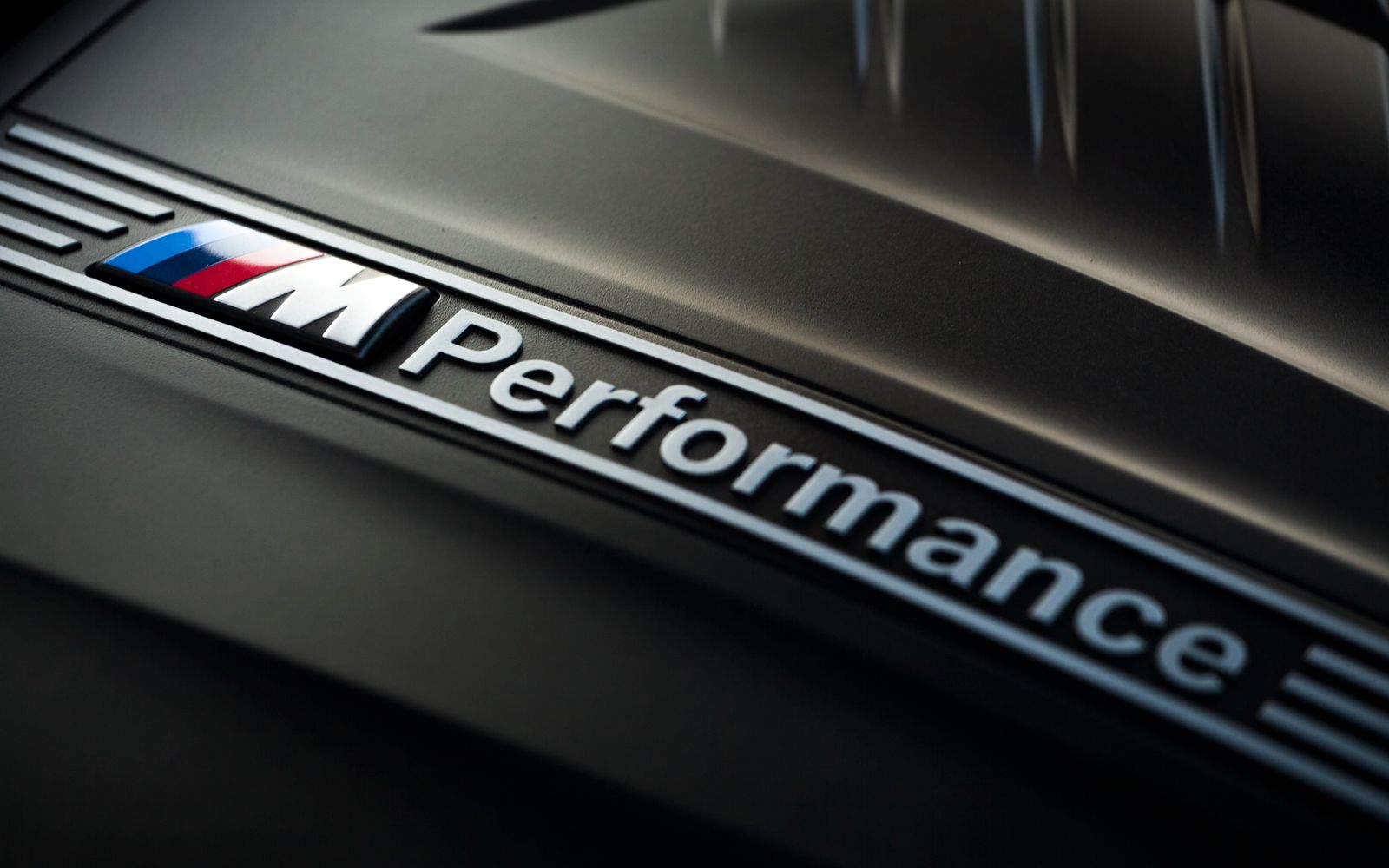 Close-up view of M Performance logo on car engine, showcasing sleek design and engineering.