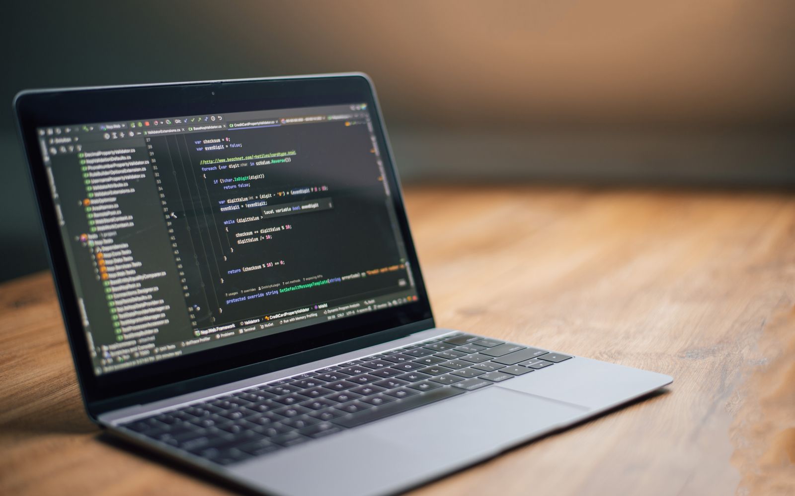 Laptop displaying software code on a wooden table, ideal for tech and programming themes.