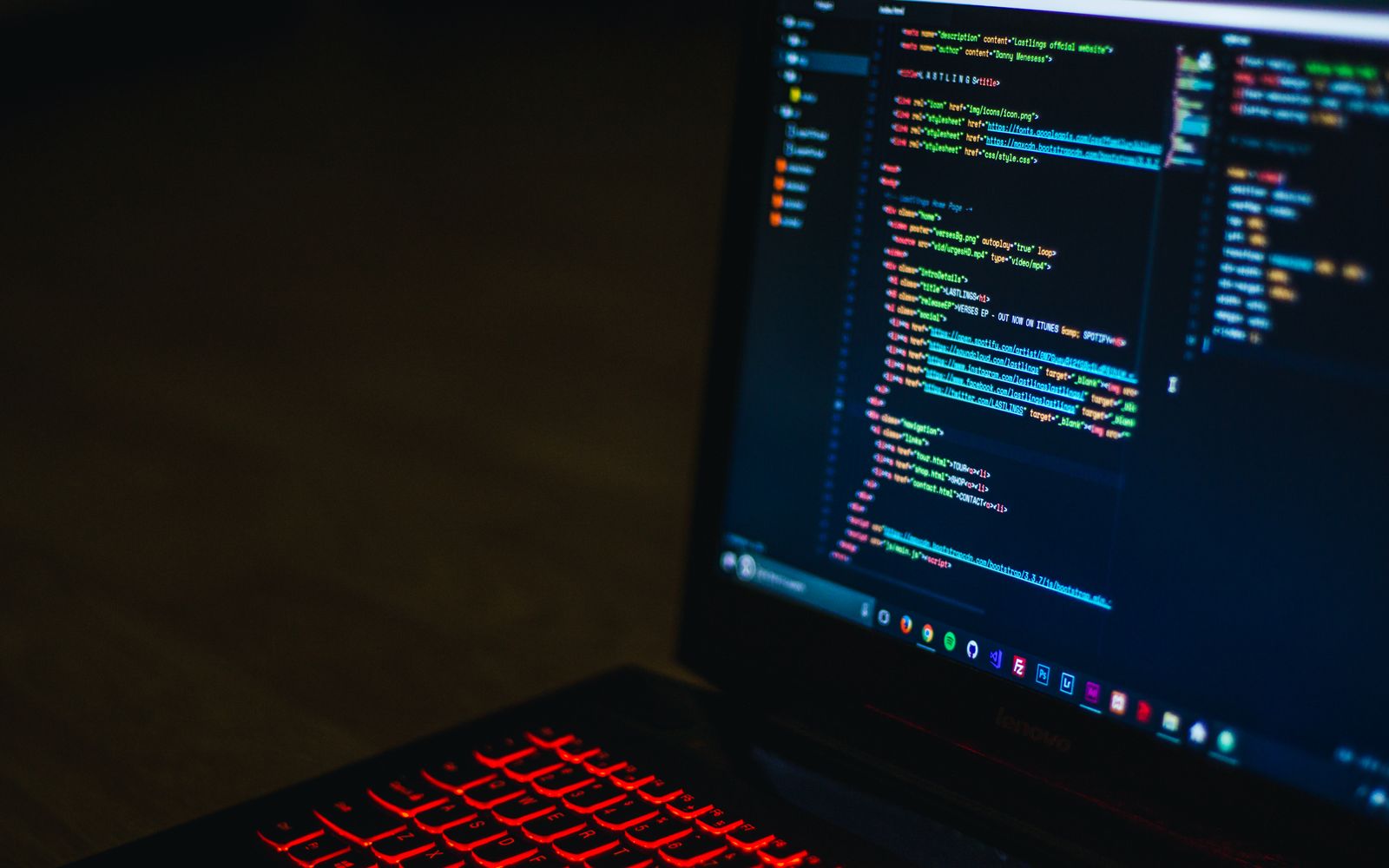 Red backlit keyboard and code on laptop screen create a tech-focused ambiance.