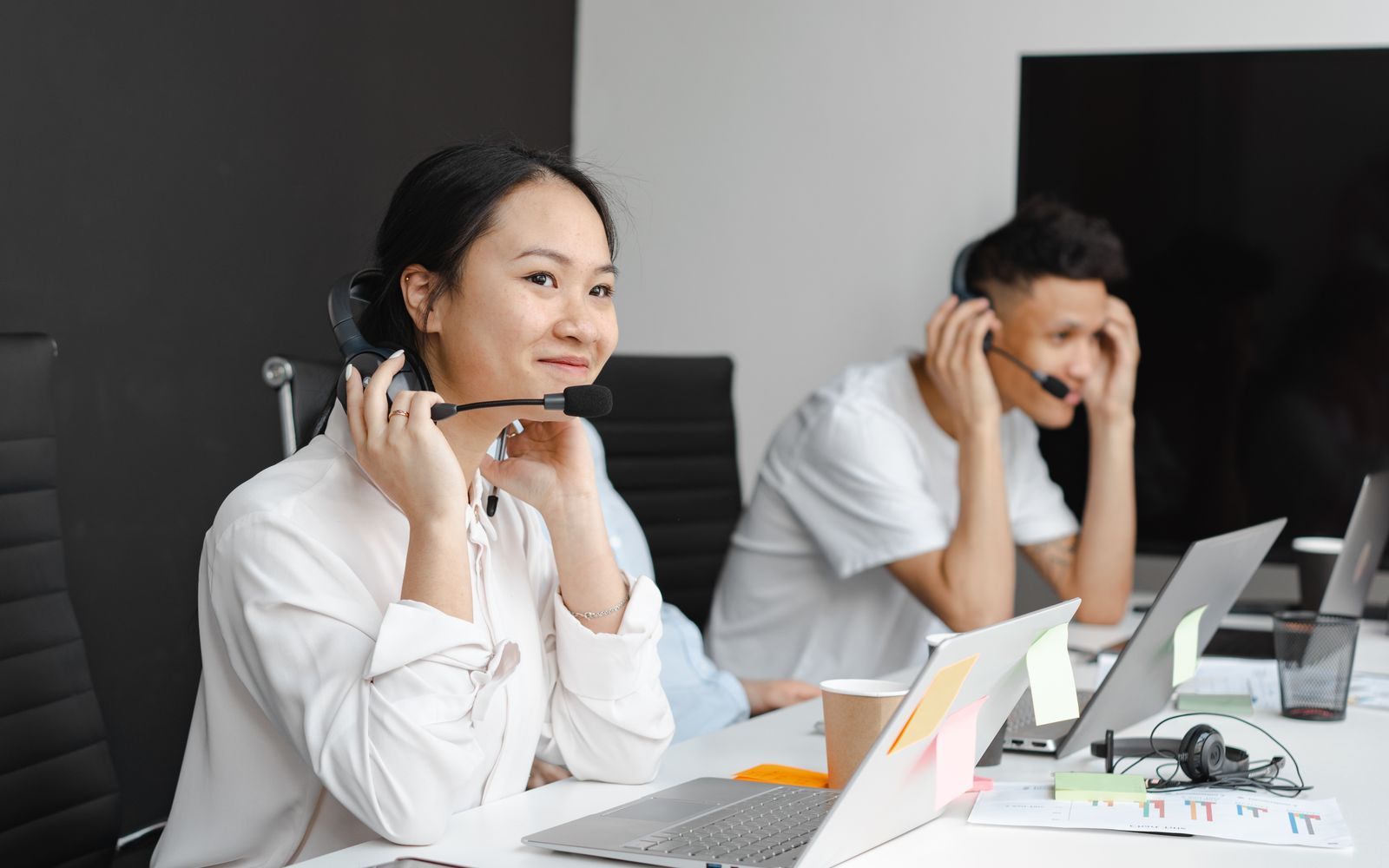 A diverse group of call center agents working with laptops and headsets in a modern office.