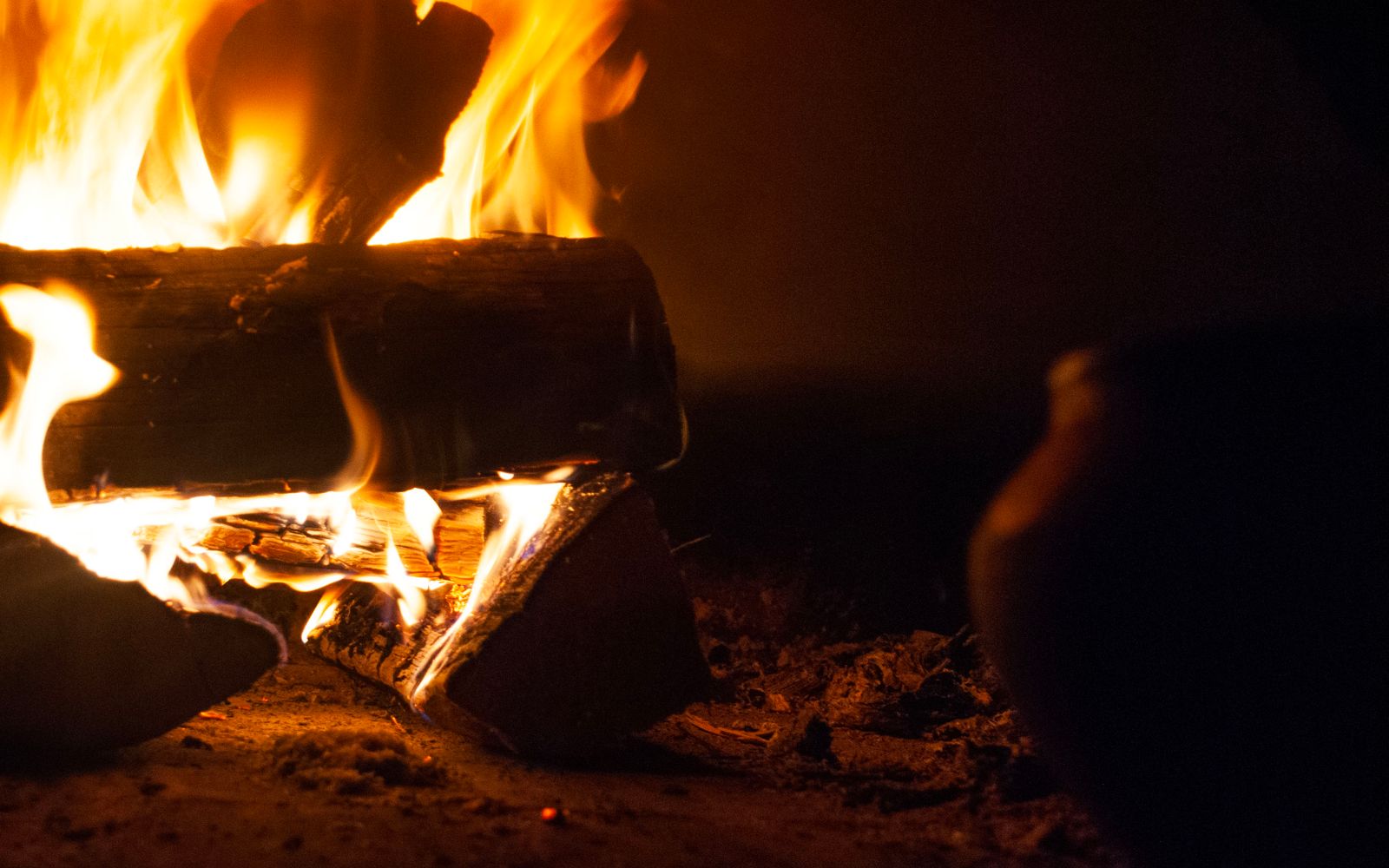 A close-up shot of warmly glowing firewood burning in a cozy fireplace, creating a soothing atmosphere.