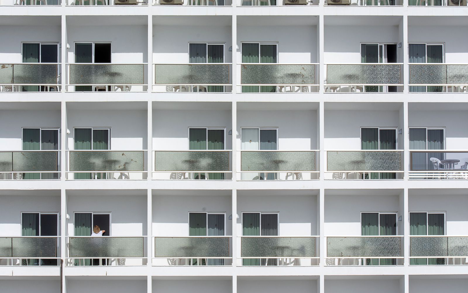 Symmetrical facade of modern apartments featuring sliding glass doors and balconies.