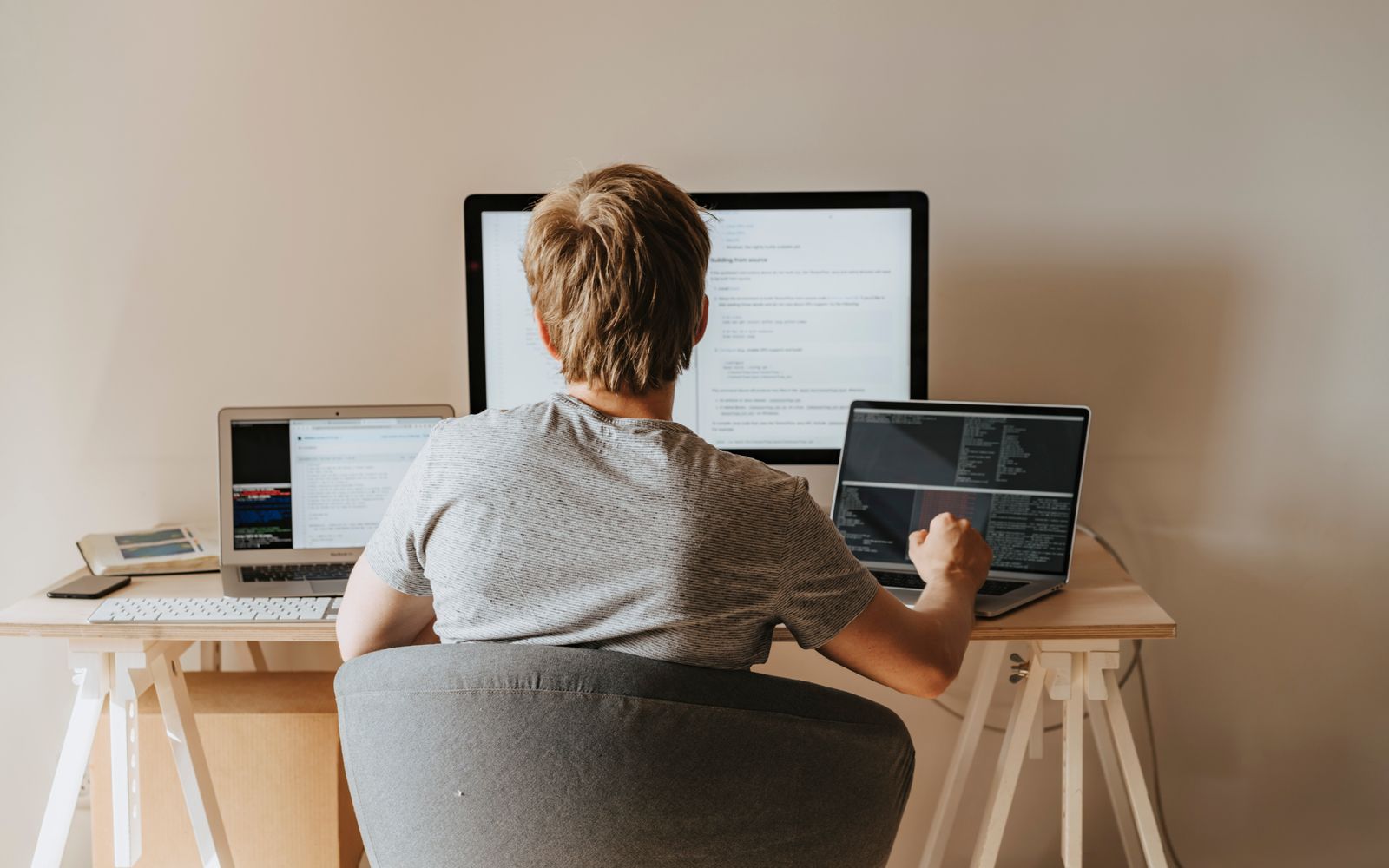 Teen programming with multiple laptops in a modern workspace. Ideal for tech and education themes.