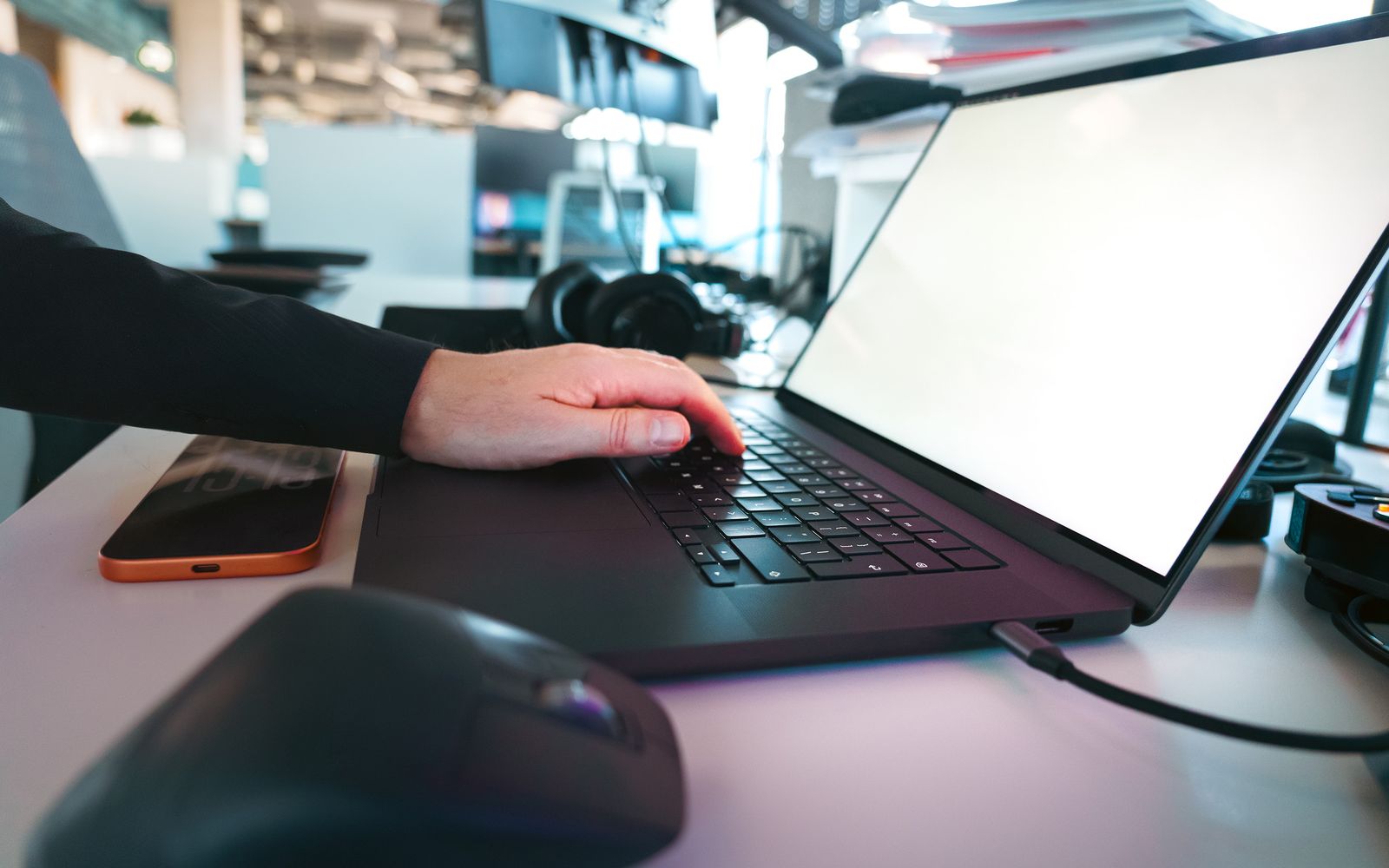 Hand typing on a laptop keyboard in a sleek office environment, showcasing modern technology.
