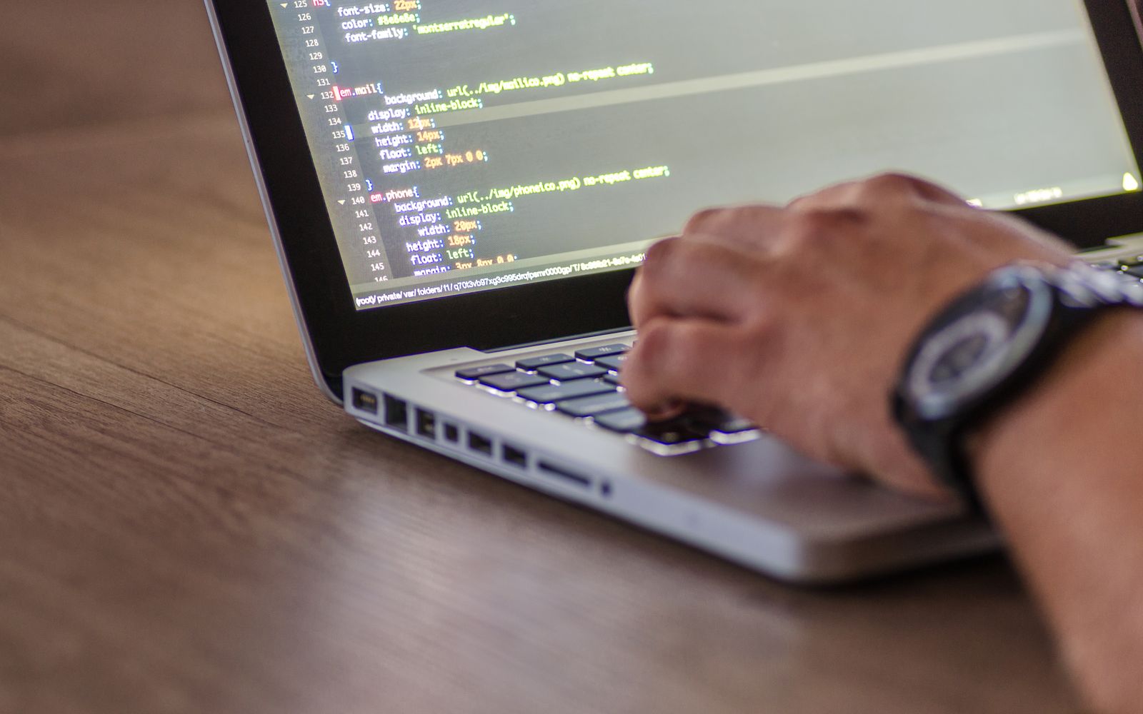 A close-up shot of a person coding on a laptop, focusing on the hands and screen.