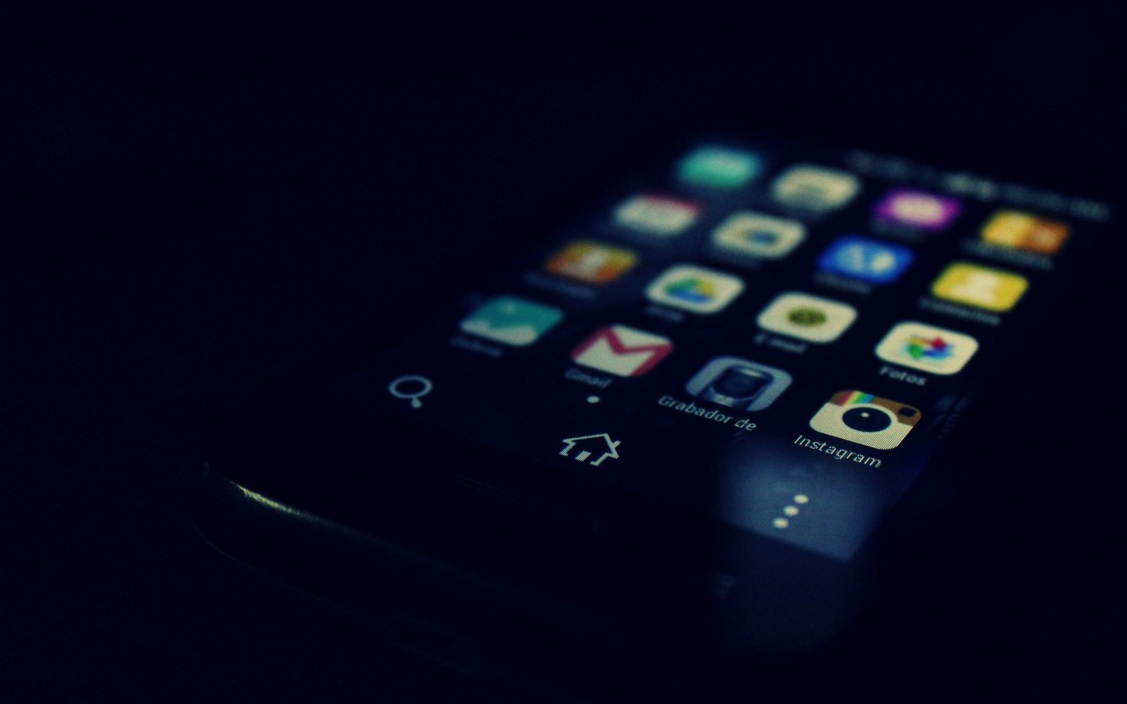 Dark-themed close-up of a smartphone screen highlighting various apps and touchscreen technology.