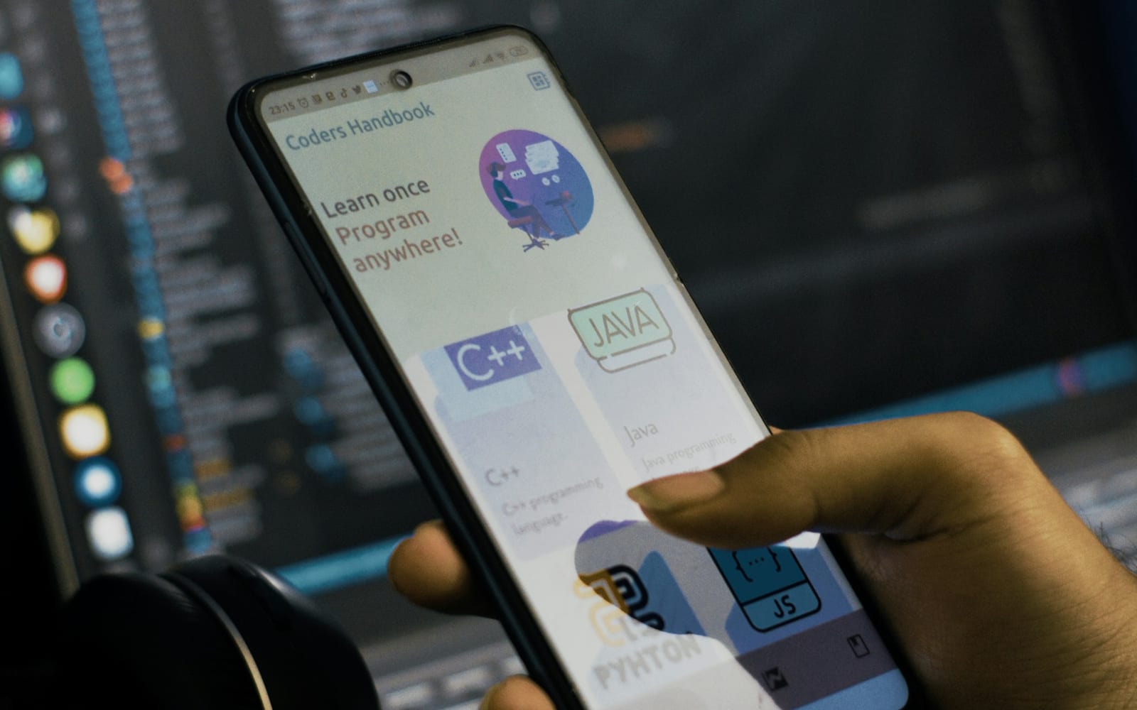 a person holding a cell phone in front of a laptop