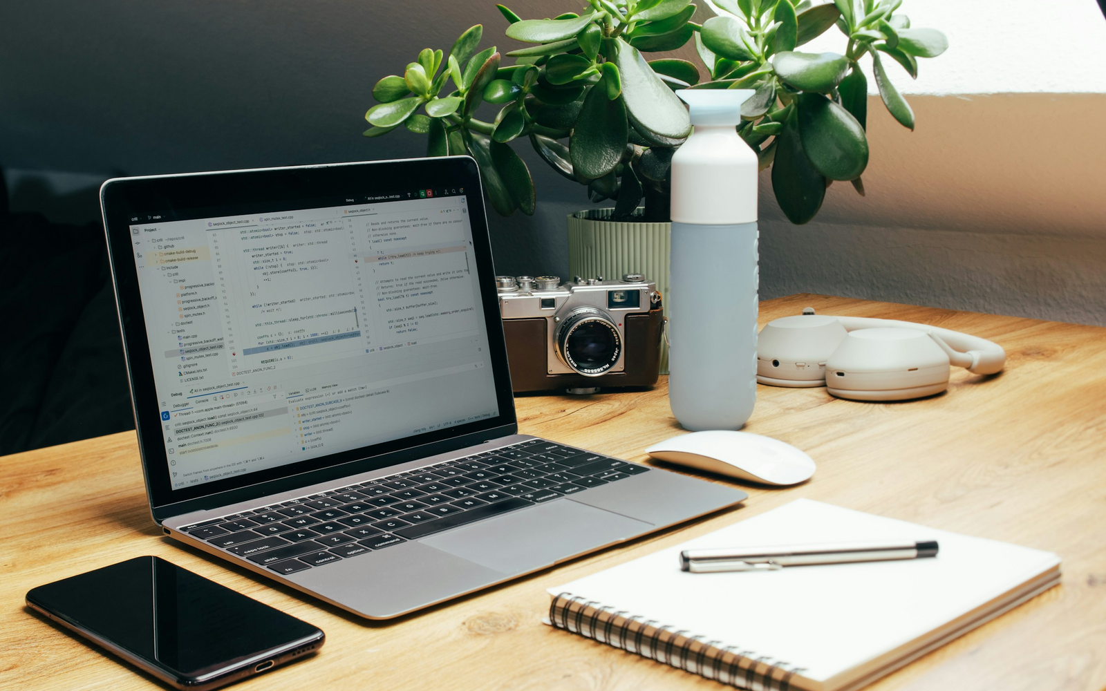 Laptop, smartphone, notebook, and camera arranged on a developer desk