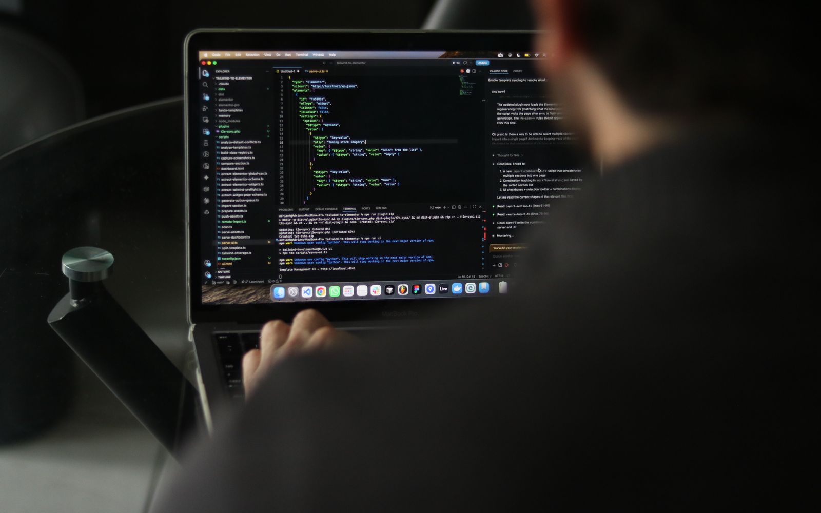 A focused developer writing code on a laptop in an indoor workspace.