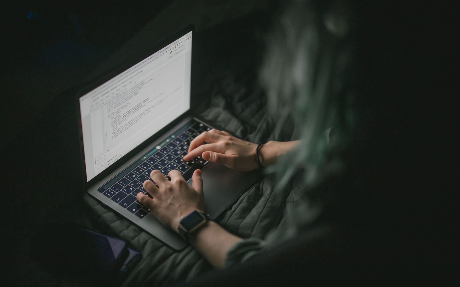 Close-up of hands typing on a laptop with code on screen, perfect for work from home and tech themes.