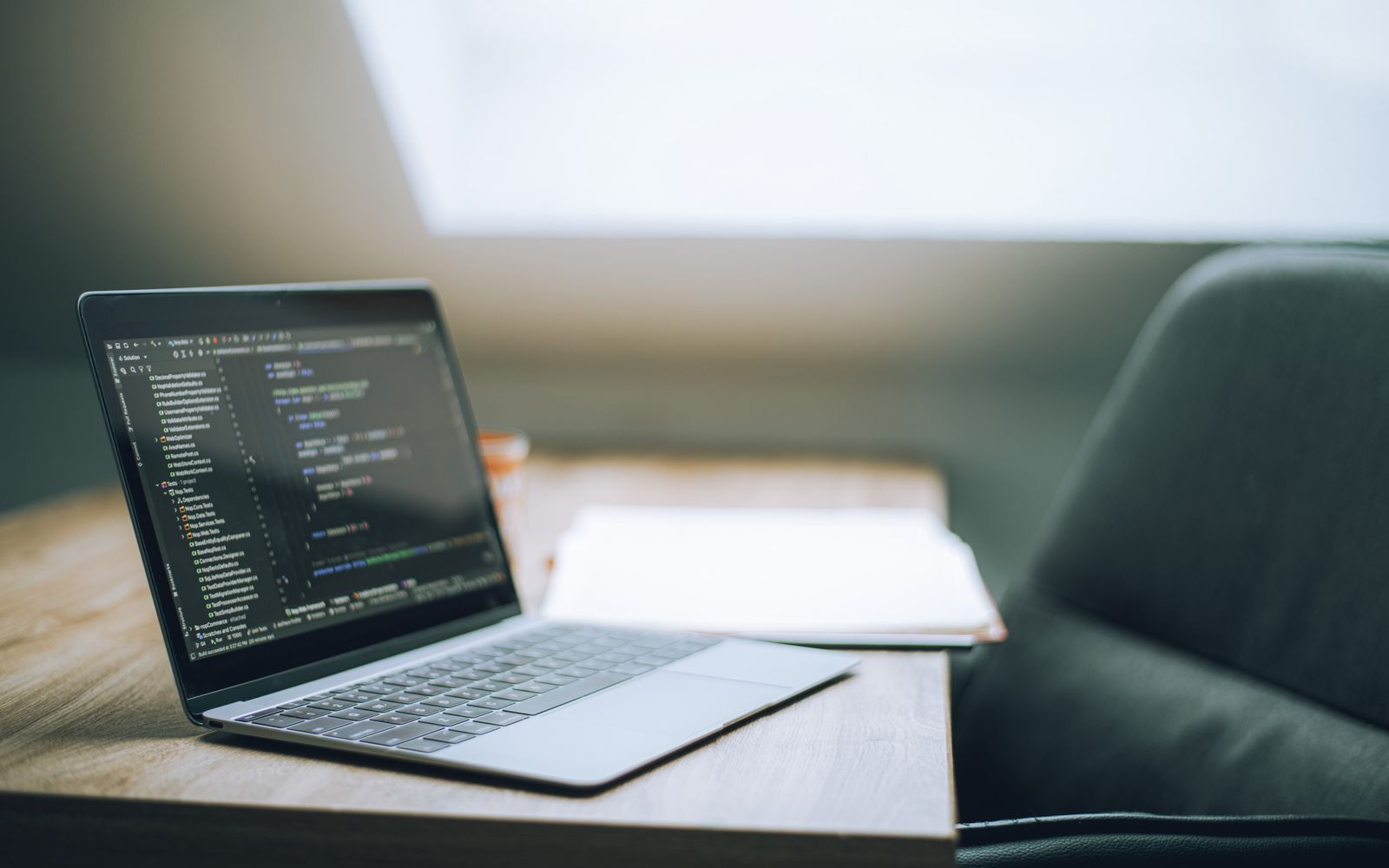 Open laptop displaying code on desk in bright, modern office setting. Ideal for tech and remote work context.