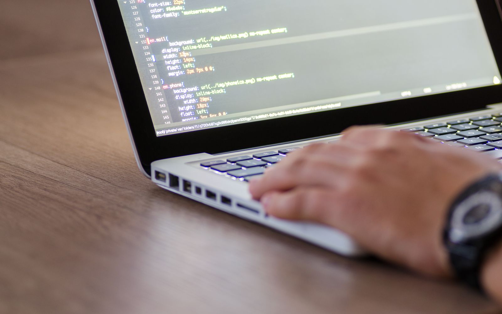 Person coding on a laptop with HTML code on screen, showcasing development work.