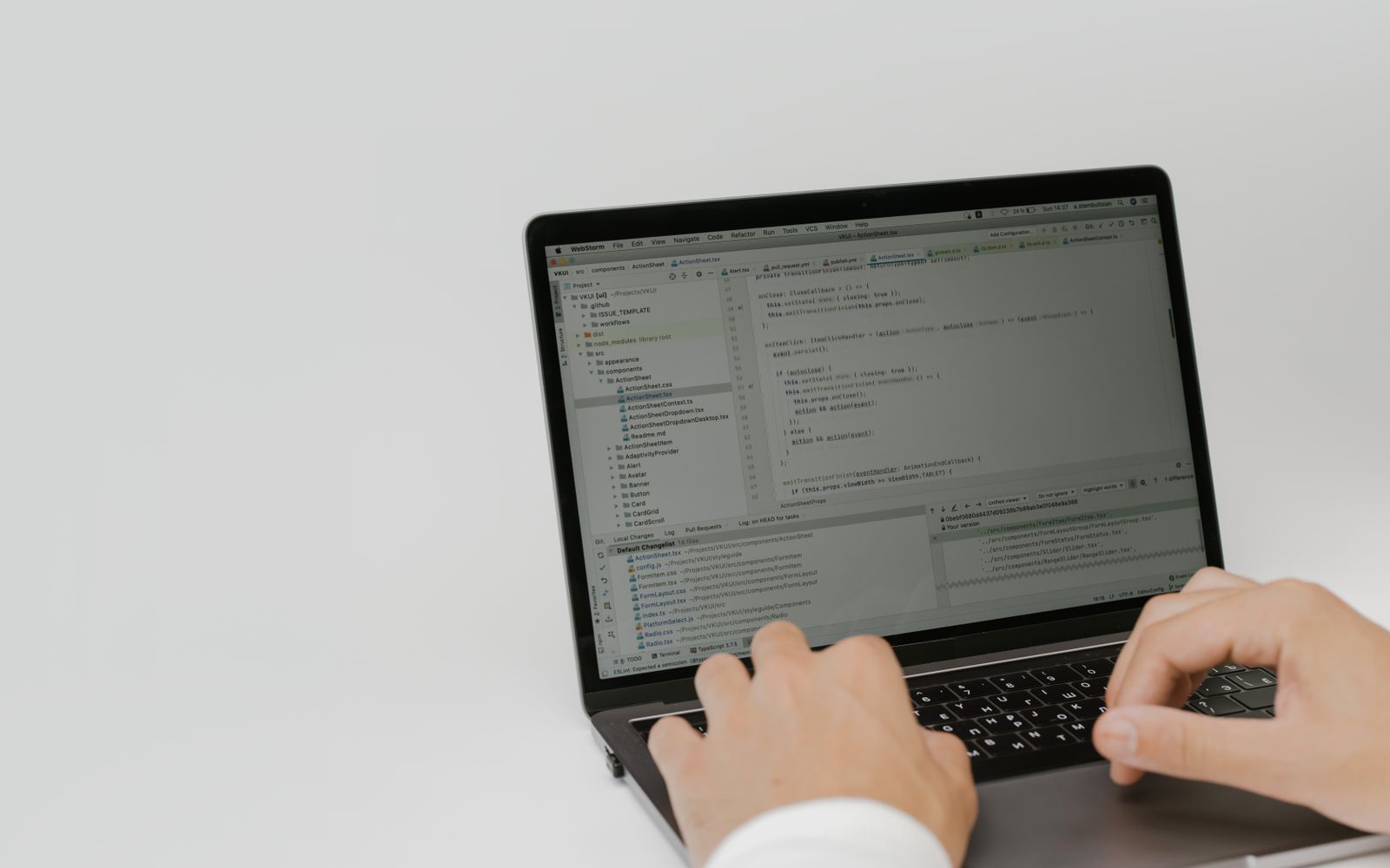 Hands typing code on a laptop in a workspace. Indoor setting focused on software development.